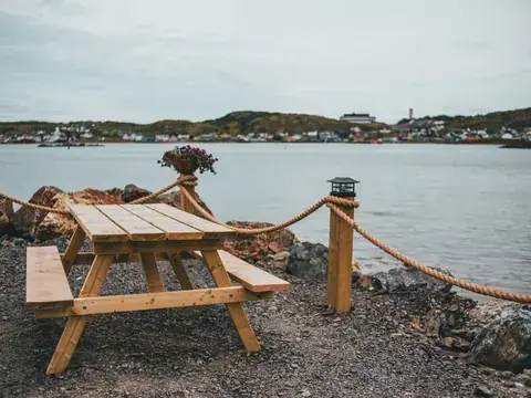Wooden picnic table and benches beside a river